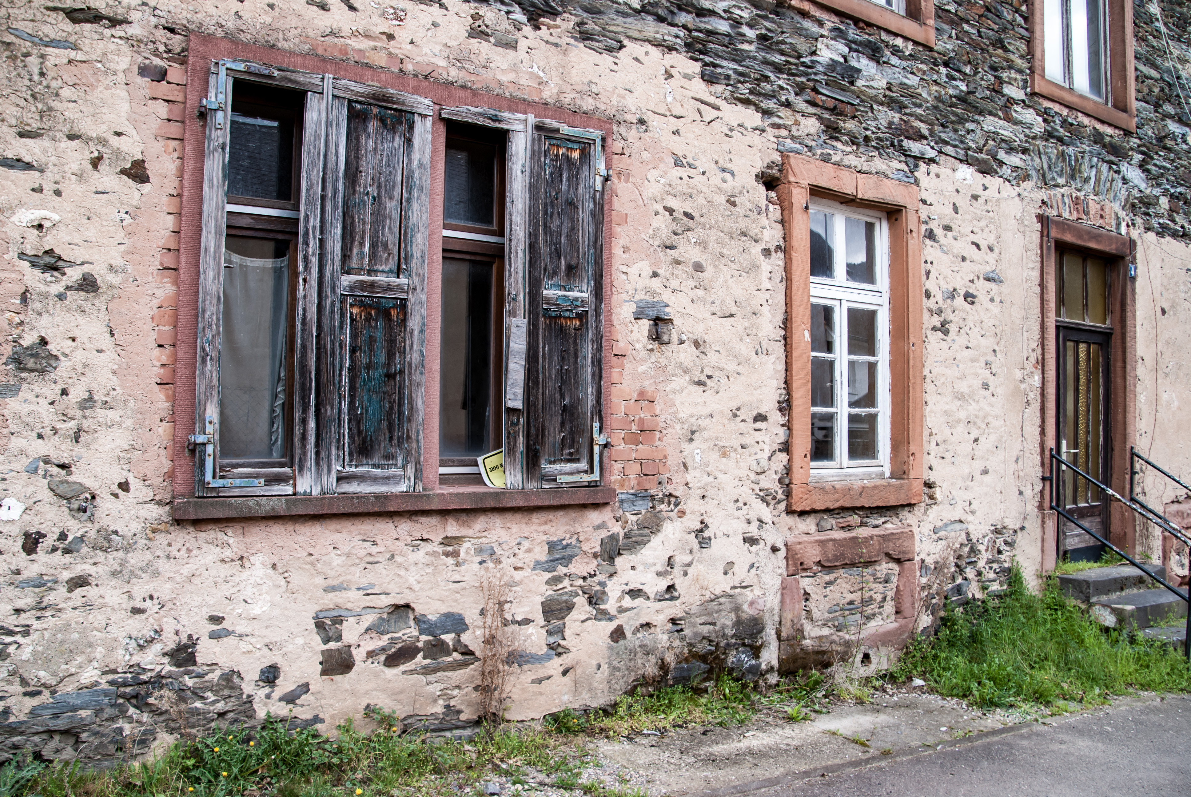 Altes, verlassenes und beschädigtes Steinhaus mit eingeschlagenen Fenstern.