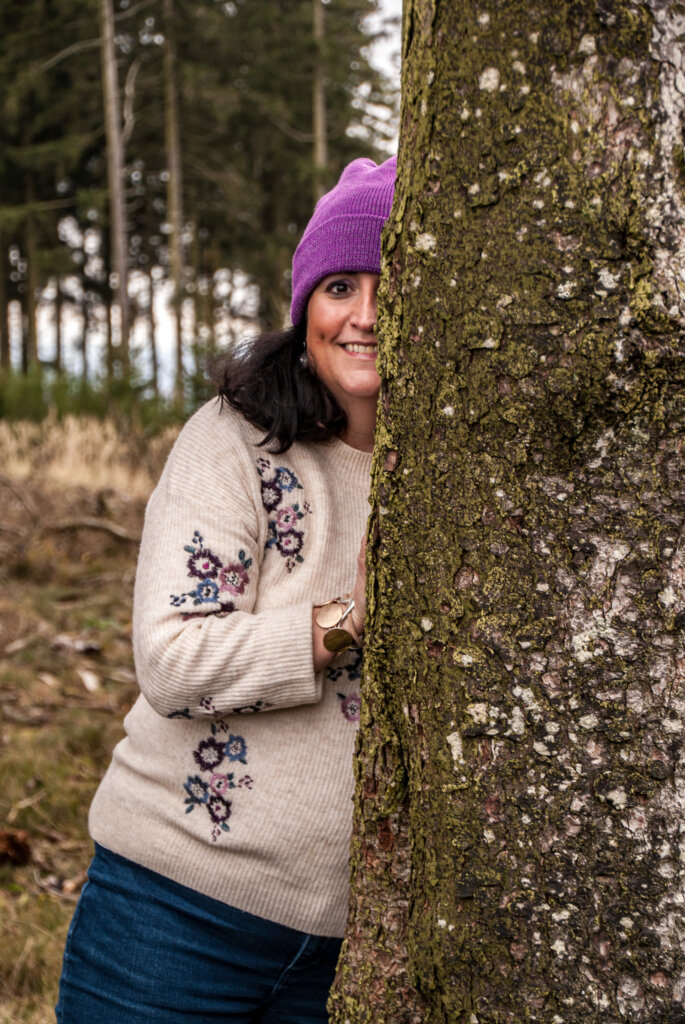 Frau im Wald hinter einem Baum