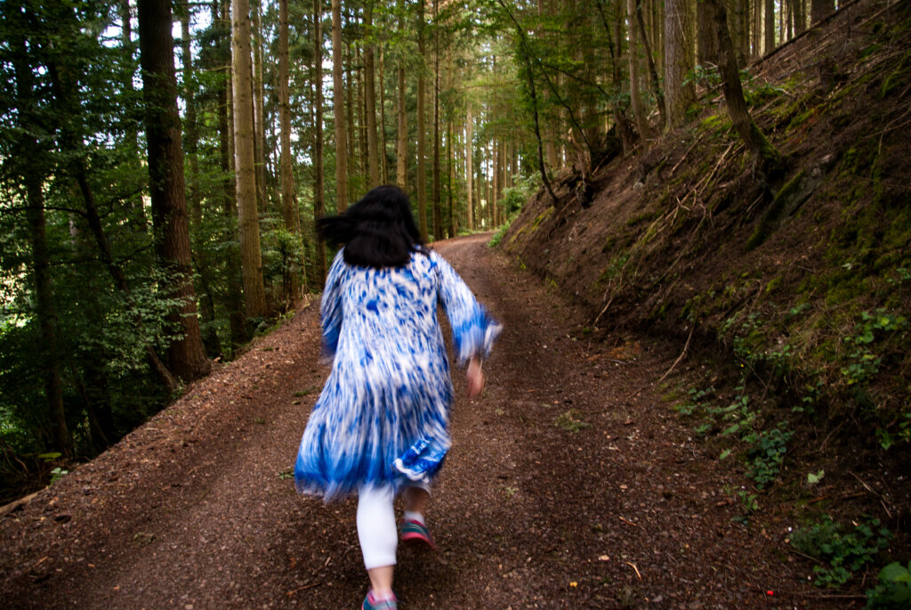 Frau in einem Kleid rennt durch einen Wald